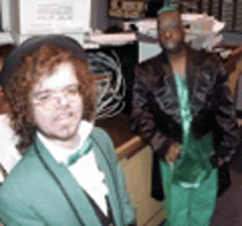 a man in a green suit is standing next to a woman in a green dress