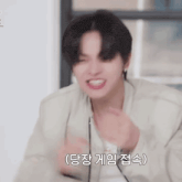 a young man in a white jacket is making a funny face with his hands in the air .