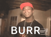 a man wearing a red hat and a black shirt with the word burr on the screen