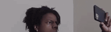 a man with dreadlocks is taking a selfie with his phone .