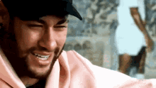 a close up of a man wearing a hat and a pink hoodie .