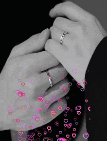 a black and white photo of a man and woman holding hands with hearts flying around them