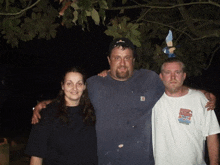 two men and a woman pose for a photo with one man wearing a white shirt that says " dirty harry "