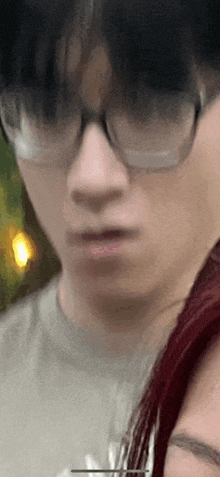 a close up of a person wearing glasses and a gray shirt .