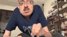 a man with glasses and a mustache wearing a blue shirt that says disarray