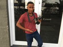 a man holding a camera standing in front of a door that says keep