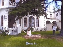 a woman sits on a blanket in front of a house with the words " come in " on the screen