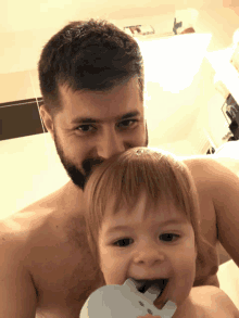 a shirtless man holds a baby in his arms