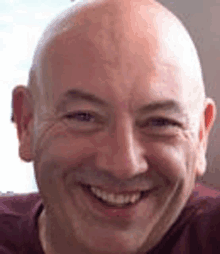 a close up of a bald man smiling for the camera .