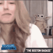 a woman is sitting in front of a stuffed animal that says the boston badass on it .