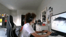 a man wearing headphones sits in front of a computer screen