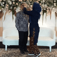 a woman in a hijab is touching a man 's face in front of a white couch