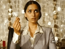 a woman in a suit is holding a cigarette in her hand .