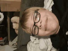 a boy wearing glasses laying on a couch