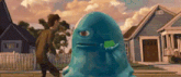 a man is standing next to a blue monster holding a green object .