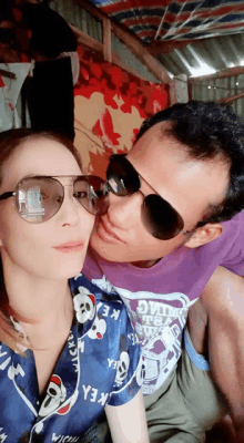 a man wearing a purple shirt that says ' king ' on it kisses a woman wearing sunglasses