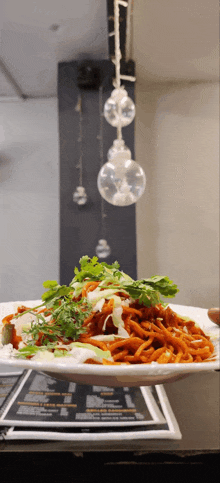 a plate of food with noodles and vegetables on a table with a menu in the background