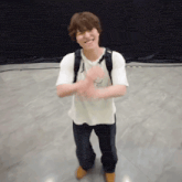 a man wearing a backpack and a white shirt is clapping