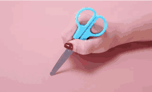 a person holding a pair of blue scissors