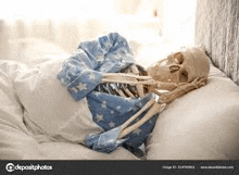 a skeleton is sleeping in a bed with a blue pajama and tie .