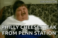 a fat man is sitting on a couch with his mouth open and the words `` philly cheesesteak from penn station '' .