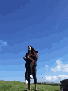 a man is carrying a woman on his shoulders on a hill