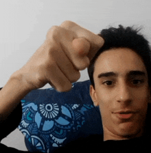 a young man wearing a blue shirt holds his fist up