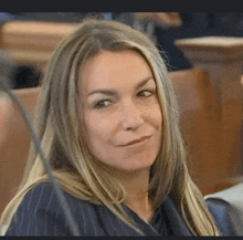 a woman with long blonde hair is sitting in a courtroom .