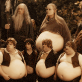 a group of fat men standing next to each other with a wizard in the background