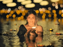 a woman is holding a lit candle in her hands while standing in the water