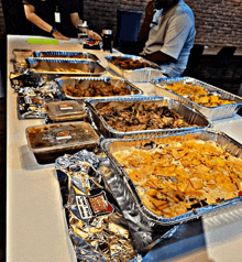 several trays of food are on a table and one of them has a sticker that says ' chicken pot pie ' on it