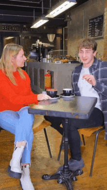 a man and a woman are sitting at a table in front of a sign that says ' beefrog '