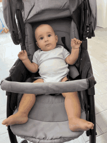 a baby is sitting in a gray stroller and looking at the camera