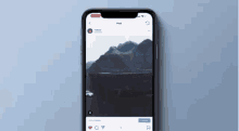 a cell phone is displaying a picture of a mountain and a lake .