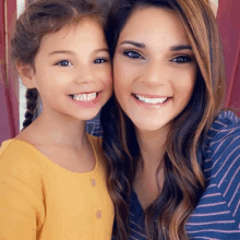 a woman and a little girl are posing for a picture together .