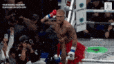 a man in a red skirt is standing in a boxing ring with a sign that says district in the background