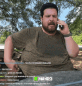 a man with a beard is talking on a cell phone with a k mando logo on the bottom
