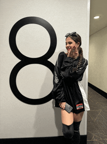 a woman leans against a wall with a number 8 on it