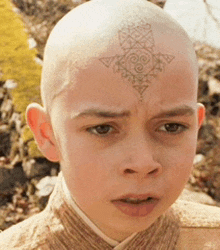 a young boy with a tattoo on his head looks at the camera