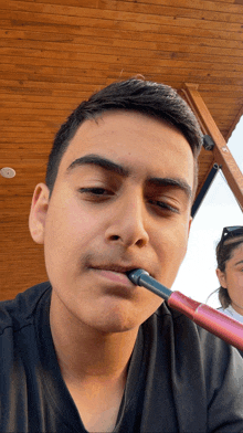 a young man is smoking a hookah with a woman behind him