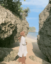 a woman wearing a hijab is standing on a beach