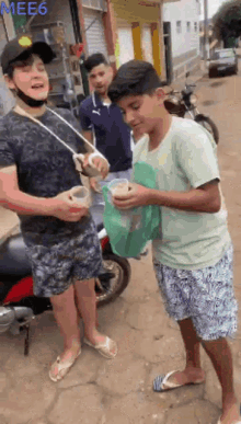 a group of young men are standing on a street and one of them is holding a cup of something