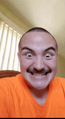 a man with a mustache is smiling and wearing an orange shirt