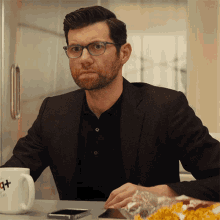 a man wearing glasses sits at a table with a mug that says ' i love you ' on it