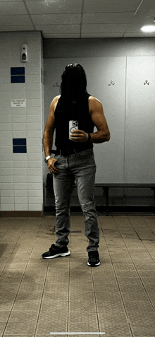 a man taking a selfie in a locker room with a sign on the wall that says no smoking