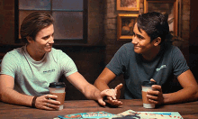 two men sitting at a table holding hands with one wearing a shirt that says ' safety ' on it