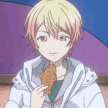 a boy in a white jacket is eating a piece of food .