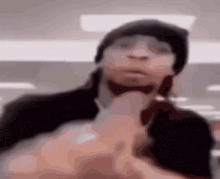 a blurry picture of a man wearing a beanie and holding a bottle .