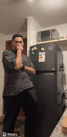 a man standing in front of a black refrigerator with the word piedra on the bottom