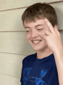 a young boy wearing a blue under armour shirt makes a funny face